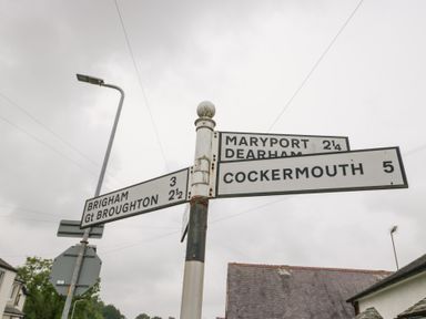 A road sign indicating directions and distances to nearby towns at 3 Nixon Terrace in Broughton Moor near Maryport