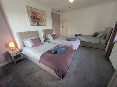 A bedroom with three beds and a nightstand at 3 Nixon Terrace Broughton Moor near Maryport