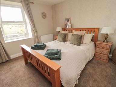 A bedroom with a wooden double bed and bedside tables with lamps at The Hollow in West Woodburn