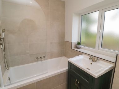 A bathroom with a bathtub and a sink next to a frosted window at The Hollow in West Woodburn
