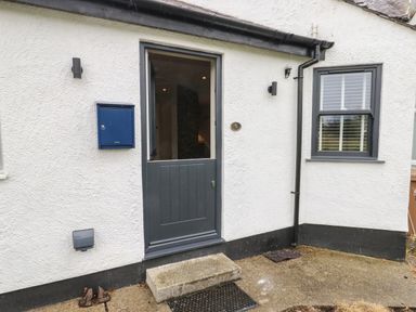 A white exterior wall with a gray half door window and mailbox at Bay Tree Cottage in Llanrug