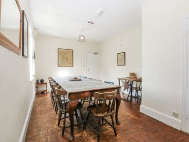 A dining room with a long table and chairs at Tawelfan in Llwyngwril