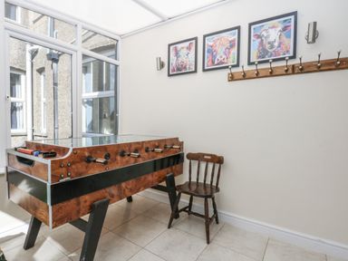 A foosball table and a chair in a sunroom at Tawelfan in Llwyngwril