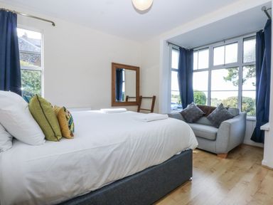 A bedroom with a bed and armchair at Tawelfan in Llwyngwril