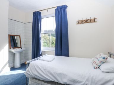 A bedroom with a bed, sink, mirror, and window at Tawelfan in Llwyngwril