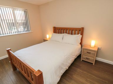 A bedroom with a wooden bed, white bedding, two bedside tables with lamps at 31A The Green in Scalby