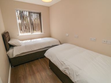 A bedroom with two single beds and vertical blinds on the window at 31A The Green in Scalby