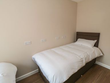 A bedroom with a single bed with white bedding against a beige wall at 31A The Green in Scalby