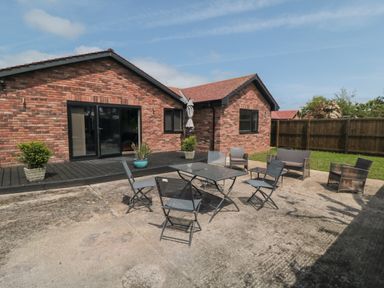 A patio area with outdoor chairs and a table outside a brick house with sliding doors at 31A The Green in Scalby