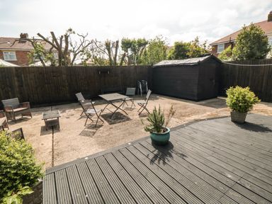 An outdoor patio area with metal chairs and a table a wooden shed and potted plants at 31A The Green in Scalby