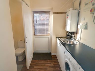 A utility room with a washing machine sink countertop and a door with window blinds at 31A The Green Scalby