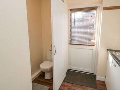 A small room with a toilet partly behind a white sliding door next to a door with blinds at 31A The Green in Scalby