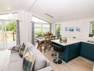 A kitchen and dining area with a sofa and table set near large windows at Eden Fields Lodge in Cupar Fife