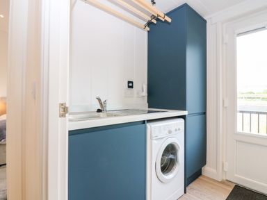 A utility room with a washing machine blue cabinets and a sink at Eden Fields Lodge in Cupar Fife