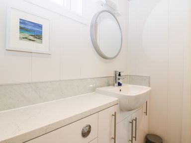 A bathroom sink with a round mirror above and a small framed picture on the wall at Eden Fields Lodge Cupar Fife