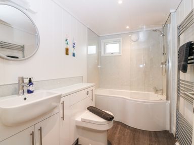 A bathroom with a sink a toilet a bathtub with a shower and a towel rack at Eden Fields Lodge in Cupar Fife