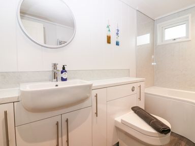 A bathroom with a sink a mirror a toilet with a towel and a bathtub at Eden Fields Lodge in Cupar Fife