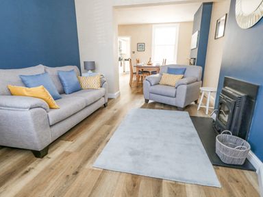A living room with gray sofas yellow and blue cushions a fireplace and a blue rug at Leos Place in Weymouth
