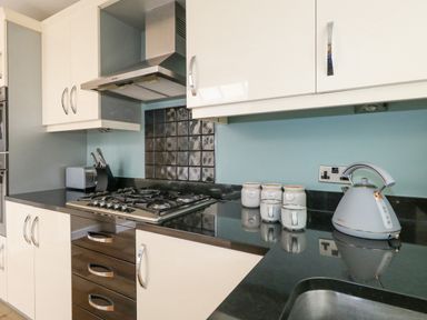 A kitchen with a gas stove kettle knife set toaster jars and a sink at Leos Place in Weymouth