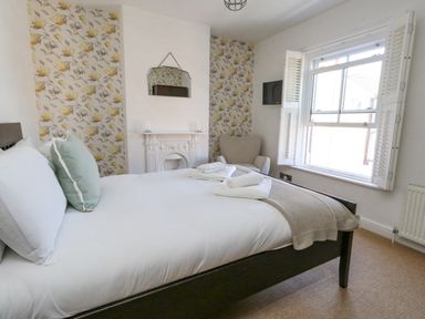 A bedroom with a bed towels an armchair a mirror and a window at Leos Place in Weymouth