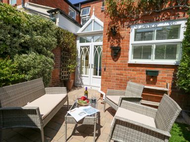 A small outdoor patio with wicker furniture and a table with fruit at Leos Place in Weymouth