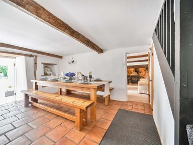 A dining room with a wooden table and benches at 2 Pigsfoot Cottages Ash Thomas near Halberton, Devon