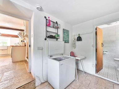 A utility room with a freezer and a door to a bathroom at 2 Pigsfoot Cottages Ash Thomas near Halberton, Devon