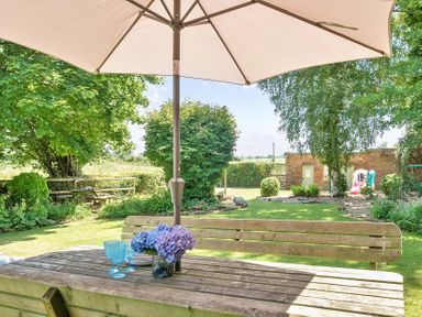An outdoor dining area with flowers and glasses at 2 Pigsfoot Cottages Ash Thomas near Halberton, Devon