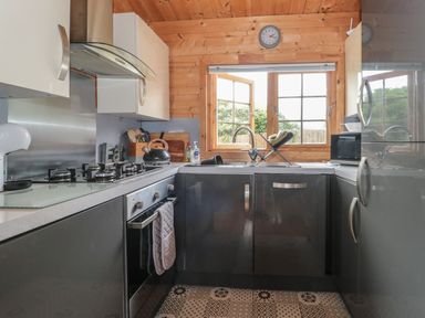 A kitchen with a stove oven sink window and cabinets at Pigsfoot Lodge in Ash Thomas near Halberton Devon