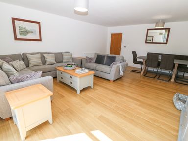 A living room with two grey sofas a coffee table side tables a dining table with chairs and framed pictures on the wall at 3 Pensyflog Barns in Porthmadog