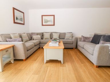 A living room with two grey sofas a wooden coffee table and framed pictures on the wall at 3 Pensyflog Barns in Porthmadog