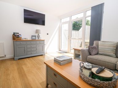 A living room with a sofa coffee table and cabinet with television at 3 Pensyflog Barns in Porthmadog