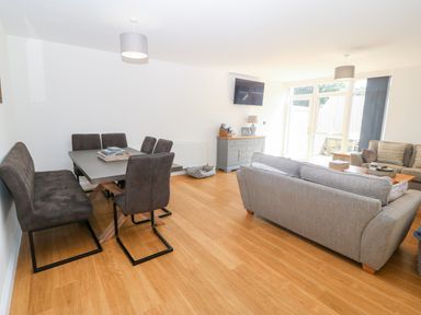 A living room with a dining table and chairs a sofa and a television on the wall at 3 Pensyflog Barns in Porthmadog