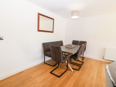 A dining area with a rectangular table and six chairs with a wall mirror and a hanging light at 3 Pensyflog Barns in Porthmadog