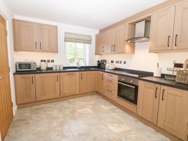A kitchen with wooden cabinets a black countertop microwave kettle toaster and oven at 3 Pensyflog Barns in Porthmadog