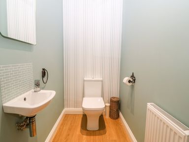 A bathroom with a toilet sink a radiator and a toilet brush holder at 3 Pensyflog Barns in Porthmadog