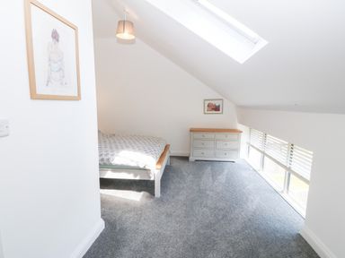 A bedroom with a bed, dresser, skylight, and window blinds at 3 Pensyflog Barns in Porthmadog