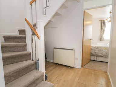 A hallway with carpeted stairs a radiator and an open door leading to a bedroom at 25 South Snowdon Wharf in Porthmadog