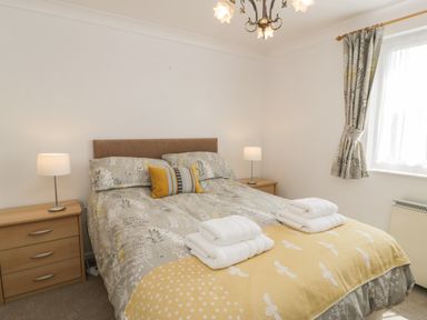 A bedroom with a double bed bedside tables lamps and a window with curtains at 25 South Snowdon Wharf in Porthmadog