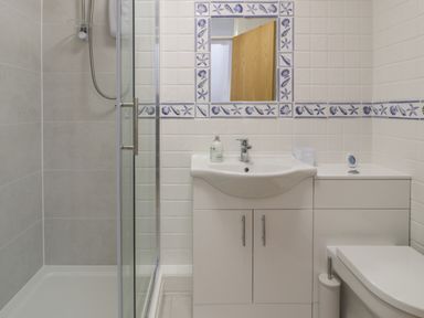 A bathroom with a shower enclosure a sink with storage cabinets and a toilet at 25 South Snowdon Wharf in Porthmadog