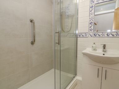 A bathroom with a shower cubicle and a sink with a mirror at 25 South Snowdon Wharf in Porthmadog