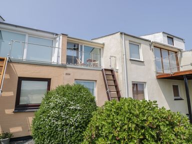 The rear exterior of a two-story house with balconies green bushes and outdoor furniture at 25 South Snowdon Wharf in Porthmadog