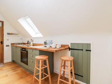 A kitchen with wooden countertops stools and green cabinets at The Rookery in Fulbrook near Burford