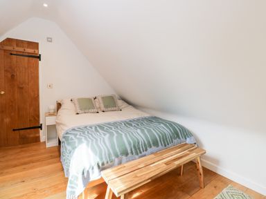A bedroom with a bed and blanket and wooden bench at The Rookery in Fulbrook near Burford