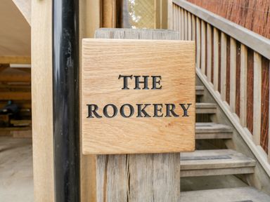 A wooden sign with the text The Rookery attached to a post next to wooden stairs at The Rookery in Fulbrook near Burford
