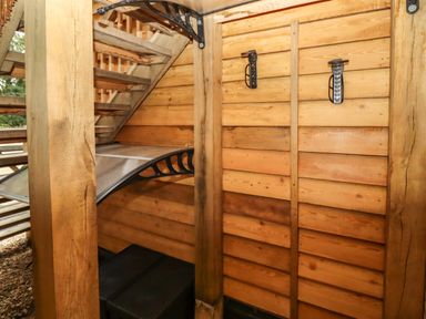 A wooden staircase with a curved metal awning and two black hooks on a wooden wall at The Rookery in Fulbrook near Burford