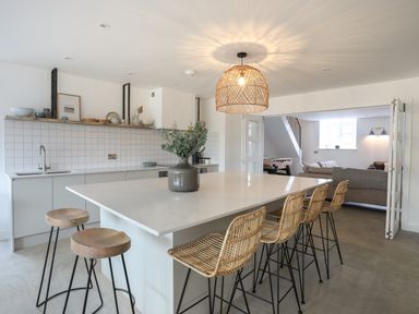 A kitchen with a large island and bar stools opening to a living room at Ysgol Fawr Big School in Benllech