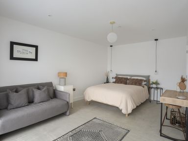 A bedroom with a bed sofa side tables lamp and a desk at Ysgol Fawr Big School in Benllech