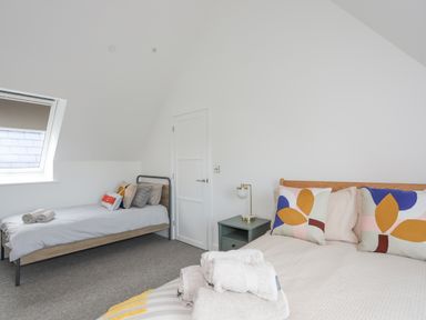 A bedroom with two beds pillows and towels a bedside table with a lamp and a window at Ysgol Fawr Big School in Benllech
