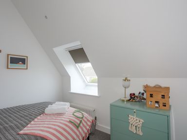 A bedroom with a bed, a window with a blind, and a green chest of drawers at Ysgol Fawr Big School in Benllech